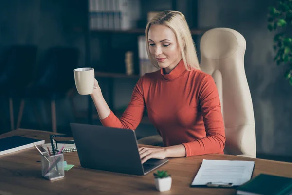 Foto blonďaté vlasy veselý pozitivní programátor pracuje na svém novém softwaru pro korporaci pracuje pro držení hrnek sedí u stolu — Stock fotografie