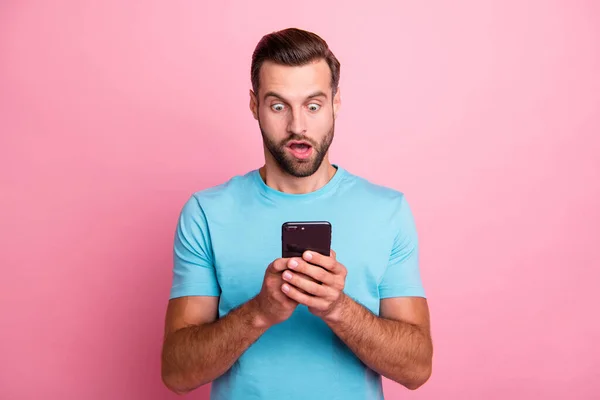 Foto de homem sorrindo louco surpreso casual com medo de mensagem recebida olhando para a tela informações sobre ser demitido isolado fundo cor pastel em azul t-shirt — Fotografia de Stock