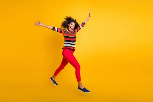 Kortingen kom ik. Full size profiel side photo of crazy funky afro american girl jump run willen lente weekend koopjes dragen gestreepte shirt rode broek geïsoleerd over gele kleur achtergrond — Stockfoto