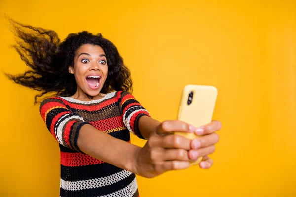 Retrato de positiva alegre afroamericana chica blogger paseo montaña rusa tener su pelo volar hacer selfie blogging video llamadas grito wow omg desgaste rayas camisa aislado amarillo color fondo — Foto de Stock