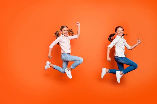 Les bonnes affaires du vendredi noir. Pleine longueur profil côté photo de positif funky deux enfants saut courir dépêcher pour les réductions d'automne porter des vêtements décontractés isolé couleur orange arrière-plan — Photo