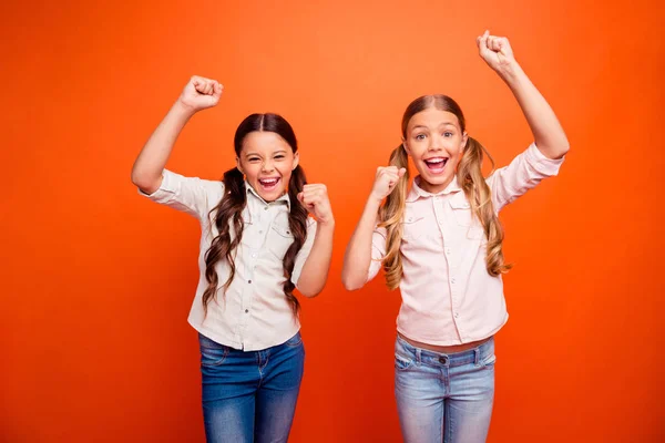 Portret van extatische twee kinderen meisje winnen concurrentie voelen gek schreeuw ja verhogen vuisten dragen moderne outfit geïsoleerd over oranje kleur achtergrond — Stockfoto