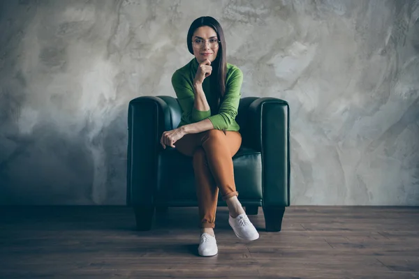 Full length body size photo of sitting pensive interested smiling joyful happy woman wearing orange pants white shoes working as content manager odizolowane szare ściany kolor betonu tło — Zdjęcie stockowe