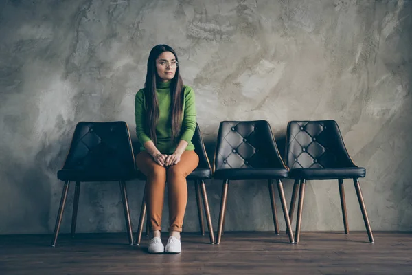 Full längd kropp storlek foto av söt kvinna väntar på sin anställningsintervju med rekryterare sitter i en av stolarna isolerad grå vägg betong bakgrund — Stockfoto