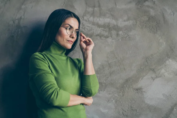 Vände foto av allvarliga säker kvinna lutar sig mot grå vägg betong bakgrund hon är isolerad över röra hennes glasögon tittar långt borta — Stockfoto