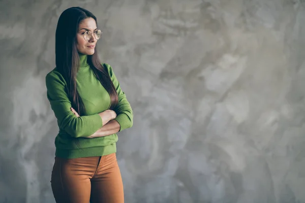 Bild av allvarlig avlyssnade självsäker kvinna tittar in i tomma utrymmen i gröna polotröja orange byxor med armarna korsade isolerade i glasögon på grå vägg betong bakgrund — Stockfoto
