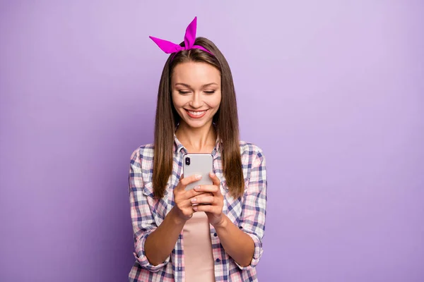 Retrato de chica alegre positiva usar su teléfono inteligente leer noticias de medios sociales disfrutar blogging usar ropa de estilo casual aislado sobre fondo de color púrpura — Foto de Stock
