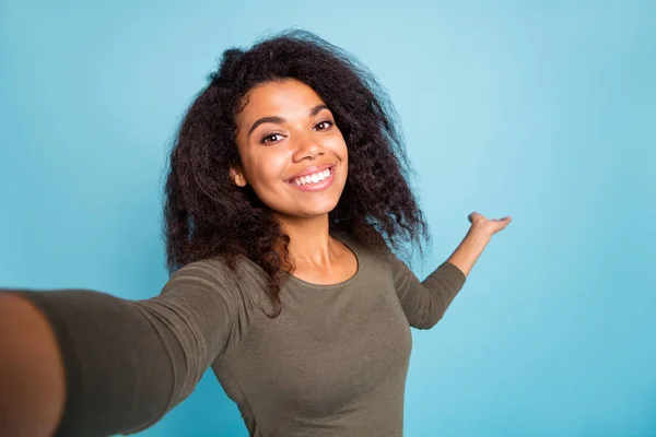 Lähikuva kuva positiivinen iloinen afro amerikkalainen turisti tyttö pitää kädestä kutsua näytä lomansa ottaa selfie videopuhelu kulumista rento tyyli paita eristetty sininen väri tausta — kuvapankkivalokuva