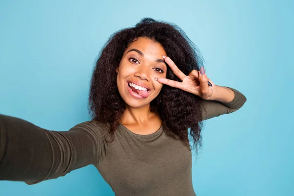 Close up photo of funny funky afro american girl blogger on trip feel fun infantile spensierato make v-signs take selfie wear trendy green sweater isolated over blue color background — Foto Stock