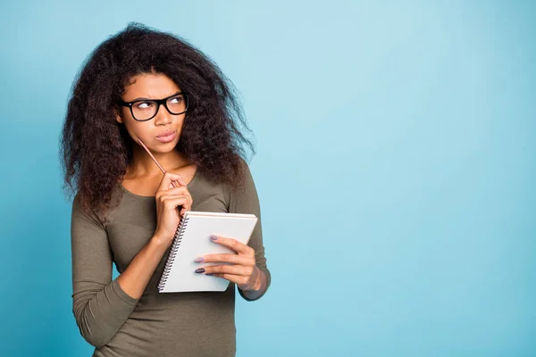 Retrato de la chica pensativa de mente oscura en gafas inteligente inteligente hipster pensar pensamientos para escribir ensayo mantenga copybook pluma desgaste traje elegante aislado sobre fondo de color azul — Foto de Stock