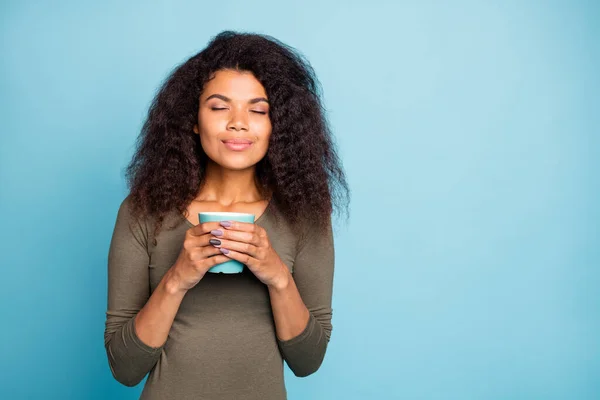 Portré bájos pozitív afro amerikai lány hold csésze bögre forró tea illata koffein ital úgy érzi, békés nyugodt kopás stílus jumper elszigetelt felett kék színű háttér — Stock Fotó