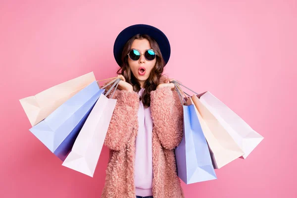 Foto von hübschen Millennial Dame tragen viele Packungen Shopper Tourismus im Ausland sehen unglaubliche Verkäufe niedrigen Preisen Einkaufszentrum tragen flauschige Jacke Sonne Spezifikationen blauer Hut isoliert rosa Hintergrund — Stockfoto