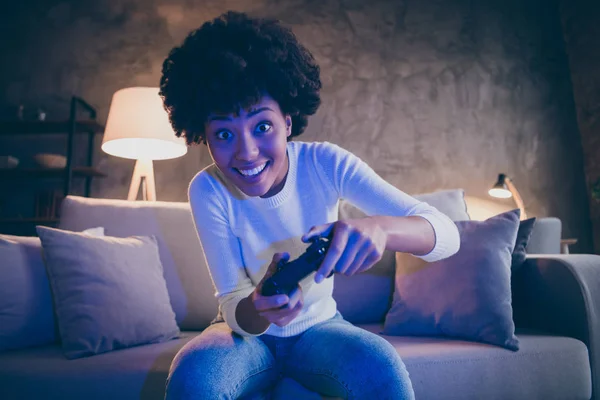 Portret van funky afro Amerikaanse meisje houden joystick spelen video race snelheid spel genieten plezier zitten divan in moderne kamer appartement huis binnen — Stockfoto