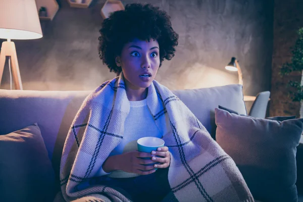 İnanılmaz bir dizi konsepti. Şaşırmış afro-amerikalı kız kanepede oturur film seyreder kahve içerken sesi soluğu çıkmayan evde kareli battaniyeyle kaplanmış gibi görünür. — Stok fotoğraf