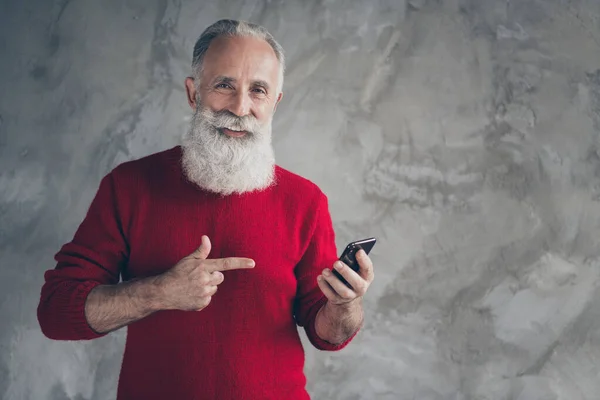 Regardez x-mas réductions. Heureux vieil homme moderne utiliser le téléphone intelligent obtenir notification directe nouvelles salutations tradition porter pull rouge isolé sur fond de couleur de mur de béton gris — Photo