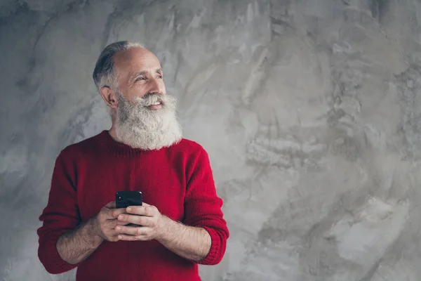 Profil côté photo de rêve positif cheveux blancs barbe vieil homme célébrer x-mas fête travail téléphone portable regarder copyspace penser noel rabais porter pull à la mode isolé fond de couleur grise — Photo