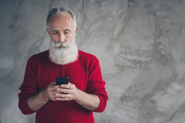 Odaklanmış çağdaş bir adamın portresi akıllı telefon metni kullanıyor. Noel aranıyor. Noel indirimleri gri arka planda izole edilmiş şık süveter giyiyor. — Stok fotoğraf
