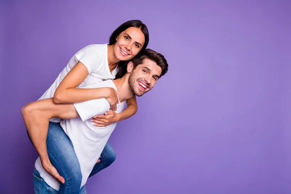 Zijprofiel foto van leuke leuke charmante paar bruin harige mensen met man dragen piggyback vrouw glimlach kieskeurig in de buurt van lege witte t-shirt geïsoleerde pastel paarse kleur achtergrond — Stockfoto