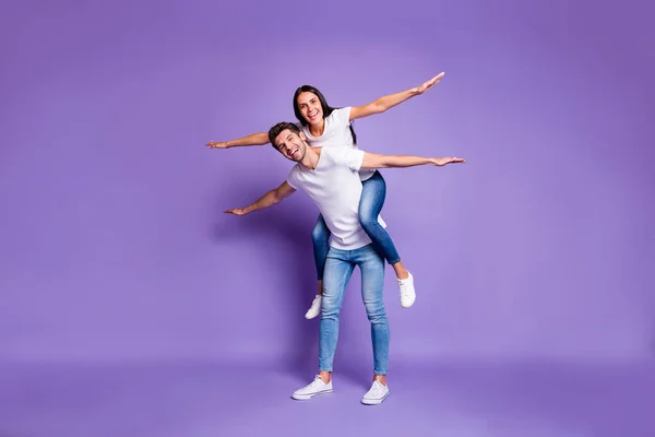 Tamanho total do corpo foto de casal positivo animado alegre com ela montando suas costas com braços para os lados em calçado branco t-shirt jeans jeans isolado pastel cor violeta fundo — Fotografia de Stock