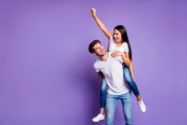 Foto av glada positiva söt ganska trevligt par två personer med hennes höjning knytnäve och honom bär henne framåt i t-shirt isolerad pastell violett färg bakgrund — Stockfoto