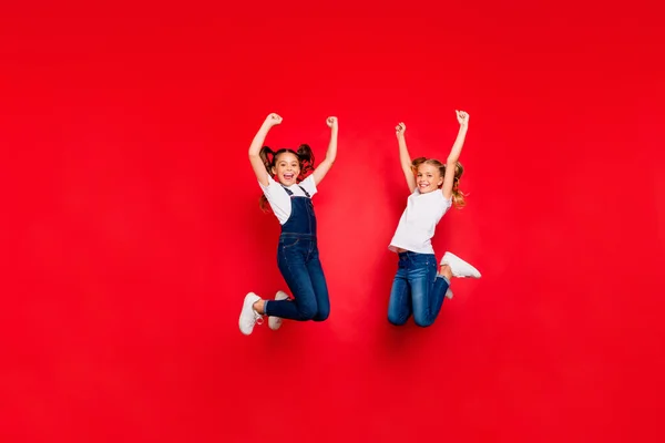 Foto de longitud completa de dos novias de pelo rubio marrón extático con colas saltar ganar x-mas lotería levantar los puños gritar sí usar ropa blanca camiseta aislado color rojo fondo — Foto de Stock