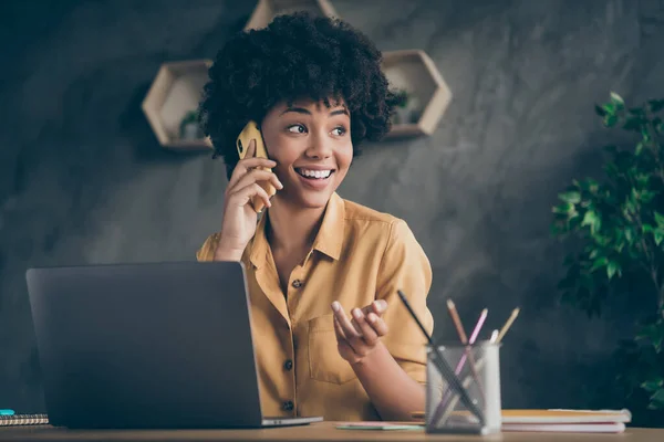 Foto de alegre positivo mestiço mulher bonita trabalhando como gerenciador de conteúdo arranjar com seus clientes por telefone sorrindo toothily — Fotografia de Stock