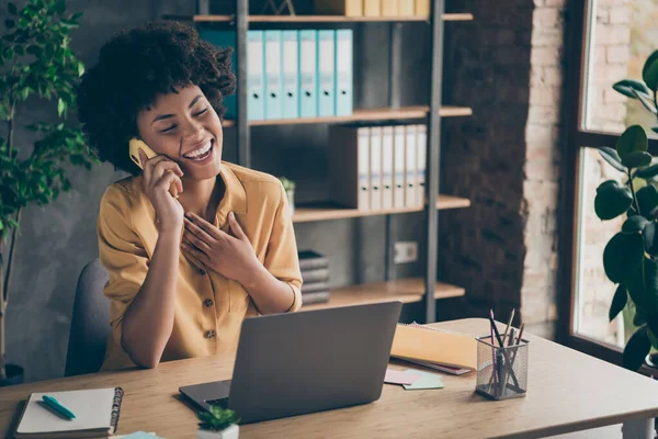 Photo of sincere cheerful mixed-race laughing girl speaking by phone with her friend colleague enjoying her break with pens notepad on desktop — Stock Photo, Image