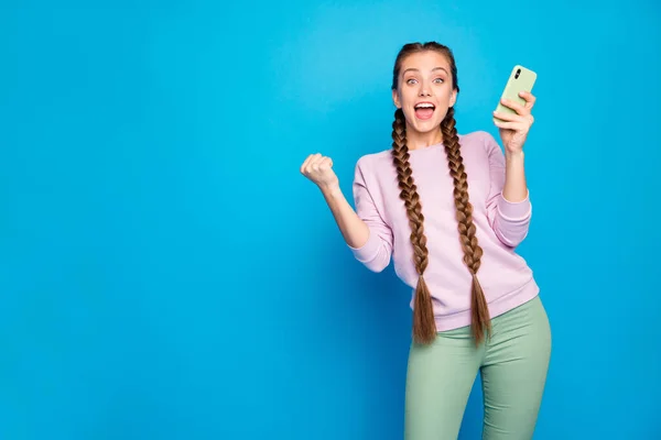Портрет восторженный сладкий молодой девушки блоггер использовать смартфон получить социальную сеть, как уведомления поднять кулаки кричать OMG Wow носить пуловер зеленые брюки брюки изолированный блеск цвета фона — стоковое фото