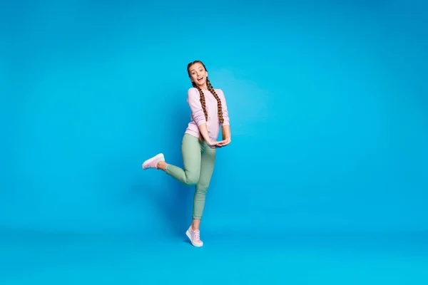 Pleine longueur photo de positive gai adolescent fille ont du temps libre sur la marche Voyage avec ses amis se sentent satisfaits porter des baskets rose tenue moderne isolé sur fond de couleur bleue — Photo