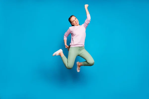 Foto de longitud completa de la señora bastante loca trenzas largas saltando campeón de la competencia deportiva alto desgaste casual suéter rosa pantalones verdes aislado fondo de color azul —  Fotos de Stock