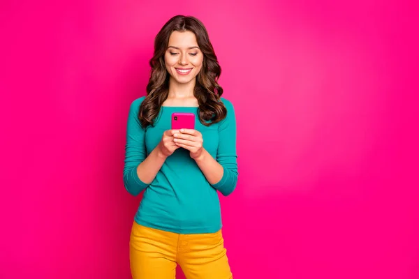 Foto van vrolijke positieve vriendin bladeren door smartphone glimlachen tandkundig het lezen van feednews geïsoleerde roze levendige kleur achtergrond — Stockfoto