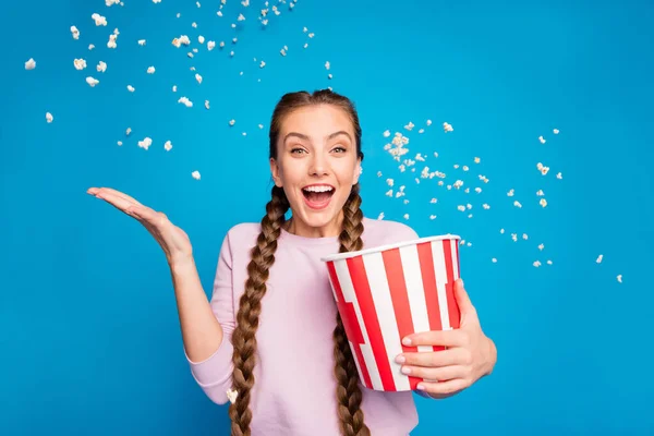 Portrait of excited enthusiastic girl hold box with flying popcorn falling in blowing air wind while watching series tv channel scream wow omg wear pink jumper isolated over shine color background — Stock Photo, Image