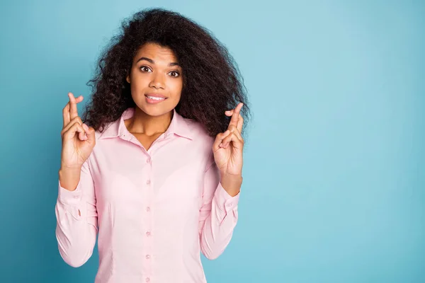 Foto von hübschen welligen dunklen Haut Dame mit gedrückten Fingern warten Untersuchungsergebnisse beten, um Bestnote tragen rosa Hemd isoliert blauer Farbhintergrund — Stockfoto