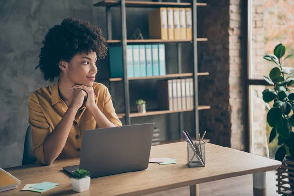 Foto van geïnteresseerd pensive schattig gemengd ras zakenvrouw in geel shirt kijken uit raam op zoek naar nieuwe ideeën te realiseren in haar project — Stockfoto