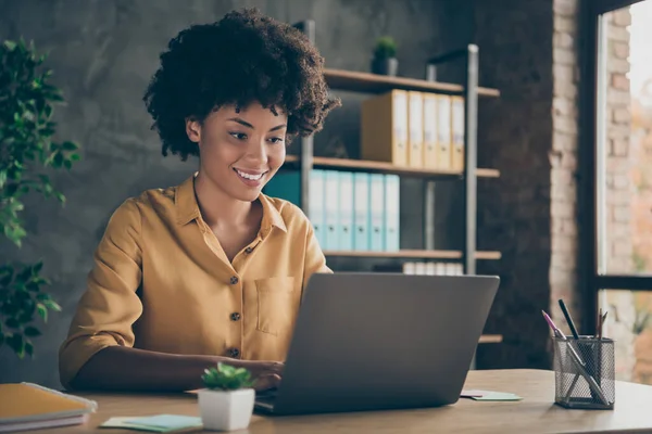 Foto de alegre positivo mestiço menina sorrindo toothily trabalhando na apresentação sobre sua corporação usando laptop no desktop — Fotografia de Stock