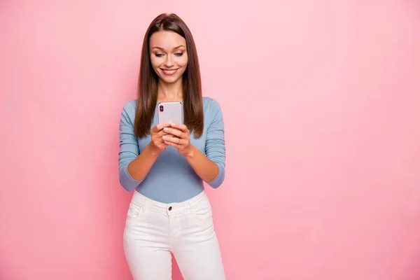 Photo of cheerful toothy beaming girl browsing through telephone near empty space leaving feedback isolated pastel color background — Stock Photo, Image