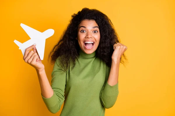 Foto de misto-raça positiva bonito bonita menina ganhou bilhetes para ir ao exterior por avião regozijando emoções animadas segurando plano isolado encaracolado ondulado amarelo vívido cor de fundo — Fotografia de Stock