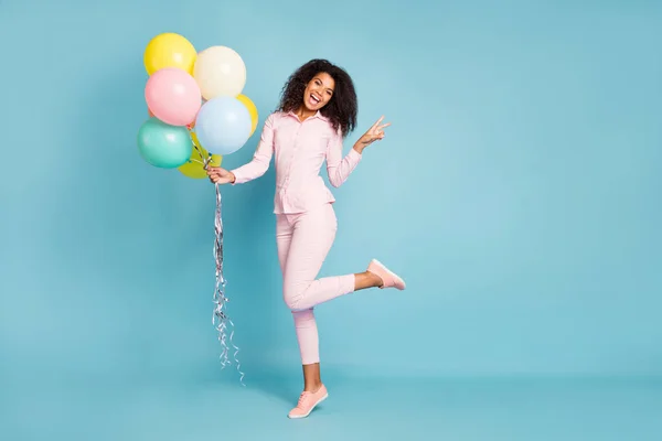 Full length photo of amazing wavy dark skin model lady holding many air balloons show v-sign symbol good mood wear pink πουκάμισο παντελόνι απομονωμένο μπλε χρώμα φόντο — Φωτογραφία Αρχείου