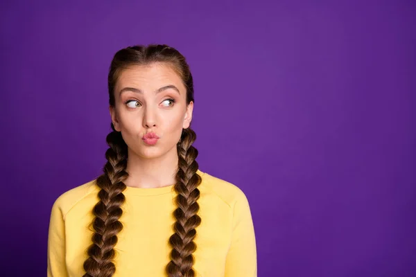 Foto von lustigen Ausdruck Dame mit langen Zöpfen Frisur Senden Luftküsse suchen schlaue leeren Raum tragen lässig gelben Pullover isoliert lila Farbe Hintergrund — Stockfoto