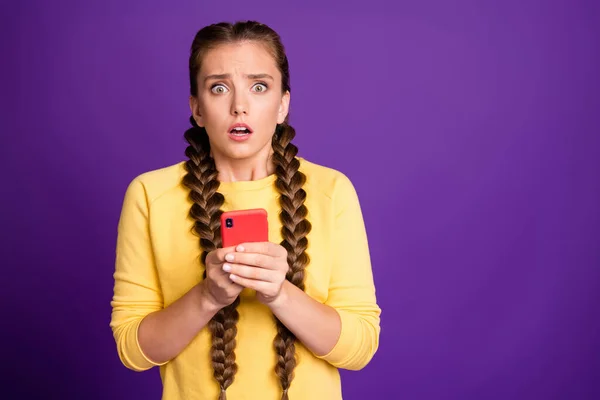 Foto von Millennial Dame mit Telefon lesen neue Fake News Kommentare offenen Mund Augen voller Angst tragen lässig gelben Pullover isoliert lila Farbe Hintergrund — Stockfoto