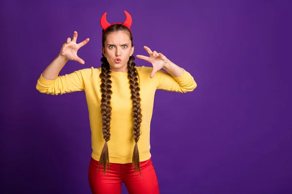 Photo de jeune femme jouant le rôle de satan à la fête d'Halloween expression effrayante porter cornes bandeau casual jaune pull pantalon rouge isolé couleur pourpre fond — Photo