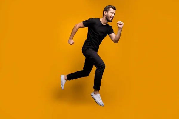 Foto em tamanho completo de cara millennial bonito pulando alta corrida shopping center preto sexta-feira oferece temporada desgaste rápido preto t-shirt calças isoladas cor amarela fundo — Fotografia de Stock