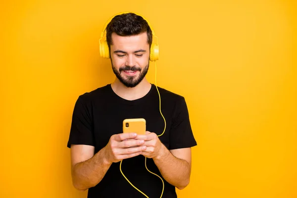 积极快乐的男人的画像听音乐用黄色耳机在手机上搜索歌曲想选择音轨穿休闲装与鲜艳的背景隔离 — 图库照片