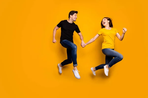 Foto em tamanho completo de cara engraçado e senhora casal saltando alto corredor shopping preto sexta-feira descontos finais temporada desgaste casual jeans preto camisetas isolado cor amarela fundo — Fotografia de Stock