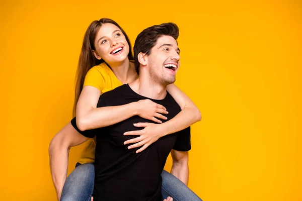 Foto de alegre positivo bonito bonito bonito casal de duas pessoas com piggyback menina montando suas costas abraçando isolado sobre fundo de cor vívida vestindo jeans jeans preto t-shirt — Fotografia de Stock