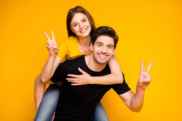 Photo of cheerful cute charming positive nice couple showing you v-sign wearing black t-shirt jeans denim piggyback isolated over vivid color background — Stock Photo, Image