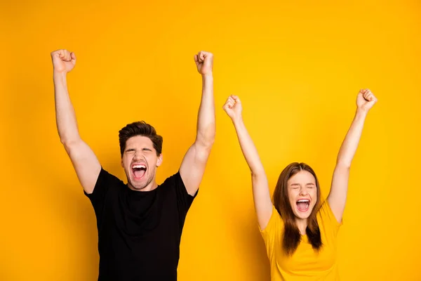 Foto de emocionado extático regocijo pareja de novio y novia de pie con la mano en alto gritando usando negro camiseta aislado color vivo fondo —  Fotos de Stock