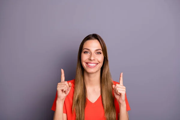 Porträtt av positiva cool flicka promotor peka pekfinger upp copyspace look försäljning visar annonser marknadsföring bära moderna kläder isolerad över grå färg bakgrund — Stockfoto