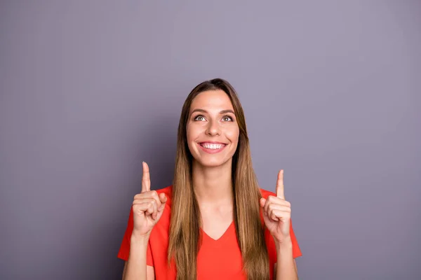 Портрет позитивної веселої дівчини вказує індекс пальця вгору на копійку показує рекламу, що носить сучасне вбрання ізольовано на сірому кольорі — стокове фото