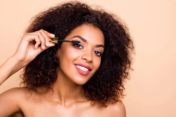 Close up foto mooi verbazingwekkend ze haar donkere huid golvend model dame handen vasthouden armen met behulp van nieuwe extra lange wimpers applicator adviseren kopen koper make-up studio naakt geïsoleerde beige pastel achtergrond — Stockfoto